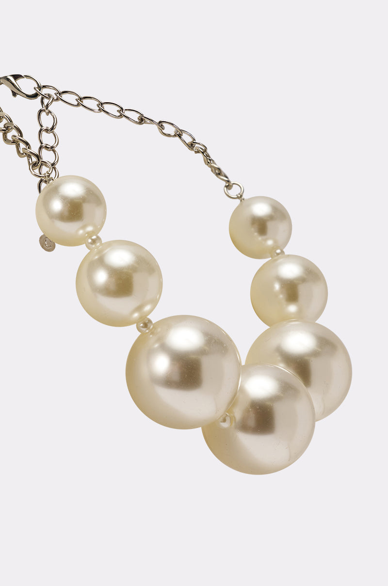 The KARL STATEMENT NECKLACE showcases oversized faux pearls in varying sizes on a sleek silver chain, elegantly displayed against a plain light background. 3