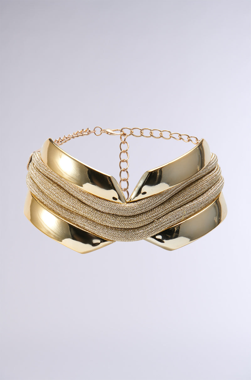 Introducing the TOO FAMOUS CHOKER NECKLACE: a gold necklace featuring a contemporary, sculptural design with smooth, reflective metal elements interwoven with multiple strands of delicate chains. This eye-catching piece includes an adjustable chain clasp and is presented against a plain, light gray background.