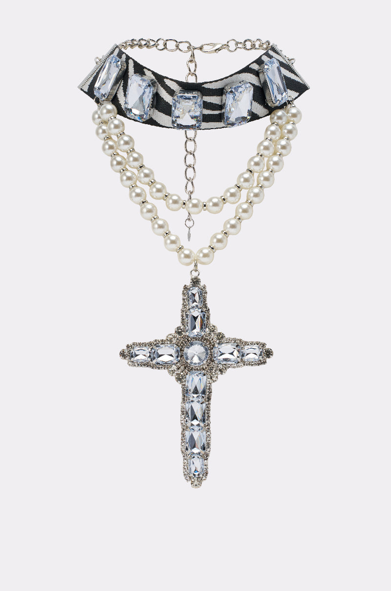 The WALK ON THE WILD SIDE STATEMENT NECKLACE features two strands of faux pearls, a jeweled cross pendant, zebra-striped ribbon, rectangular crystals, and a gold chain clasp.