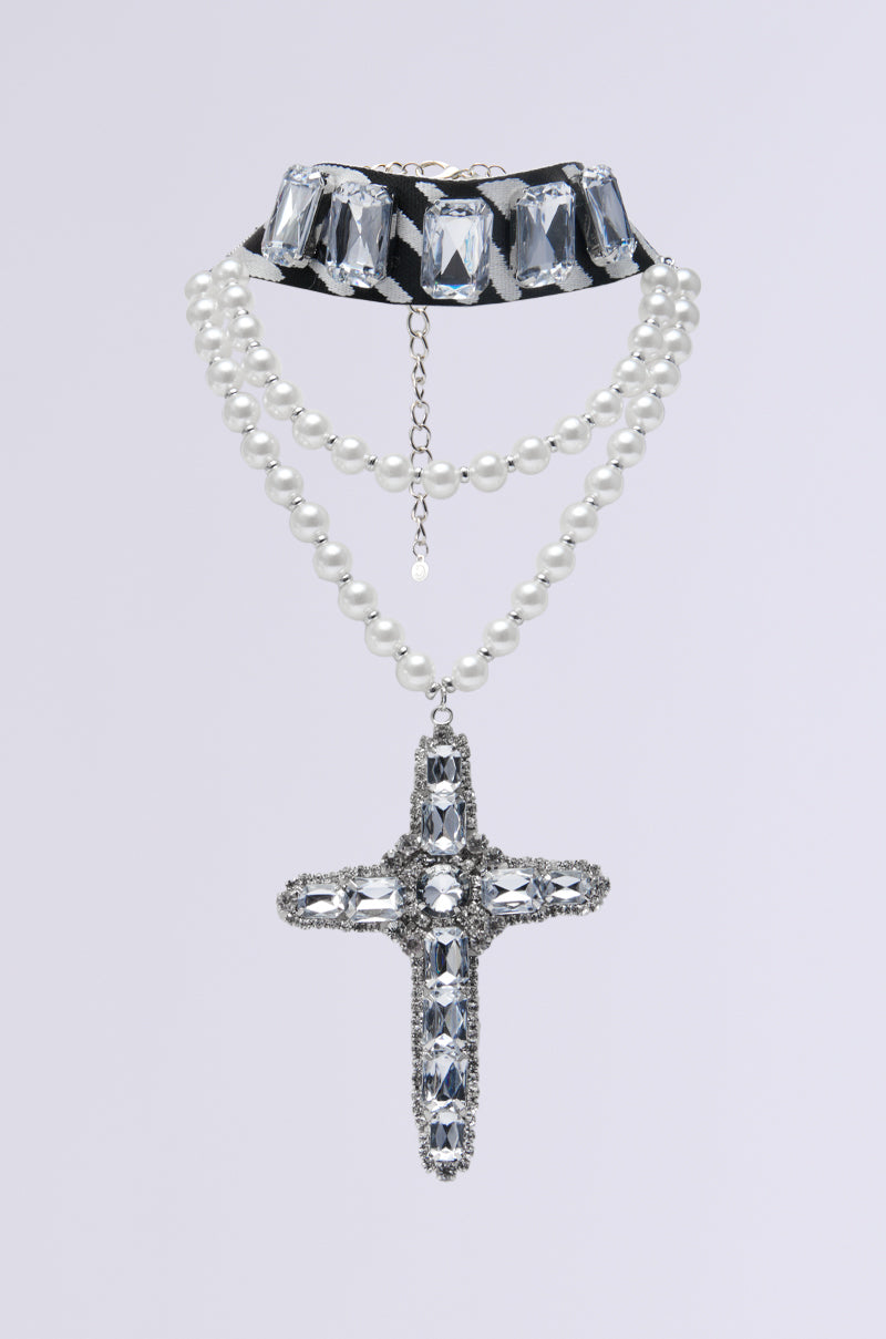 The WALK ON THE WILD SIDE STATEMENT NECKLACE showcases a black choker with clear gems, two strands of white pearls, and a jeweled cross pendant, all highlighted against a simple light background.