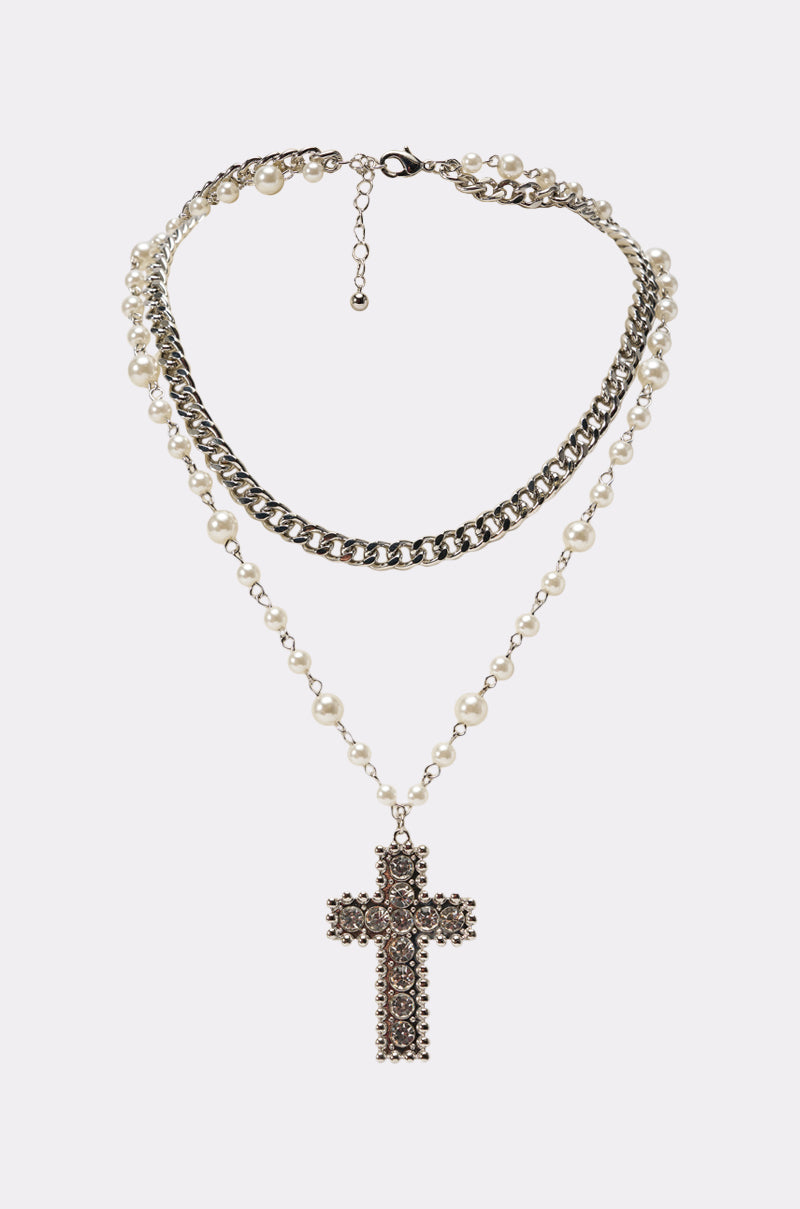 The PURL PLZ NECKLACE features a two-layer design with a silver-toned chain, pearl-beaded chain, and a large rhinestone cross pendant. This elegant statement necklace is shown on a simple light background. 0