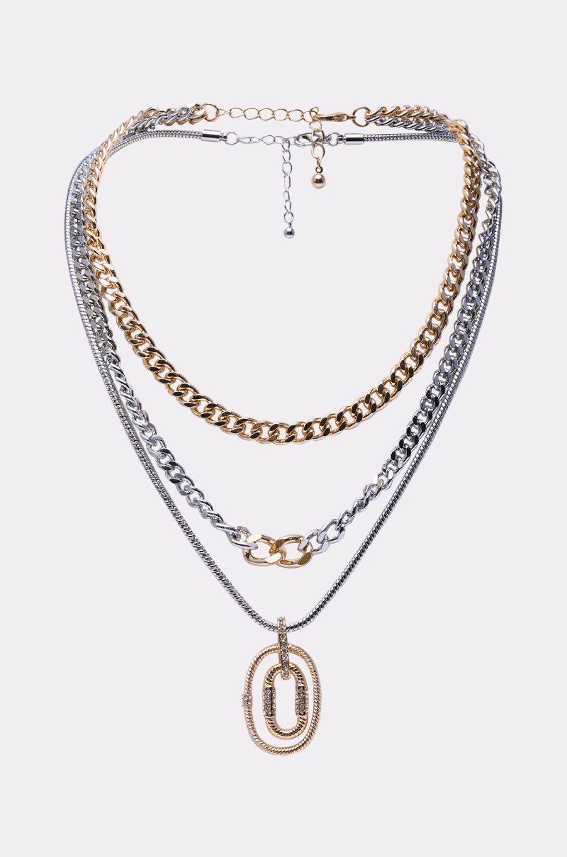 The CAN YOU NOT NECKLACE SET features five layers of gold and silver-toned mixed chains with a bold double oval pendant on the lowest layer, displayed against a plain light background. 0