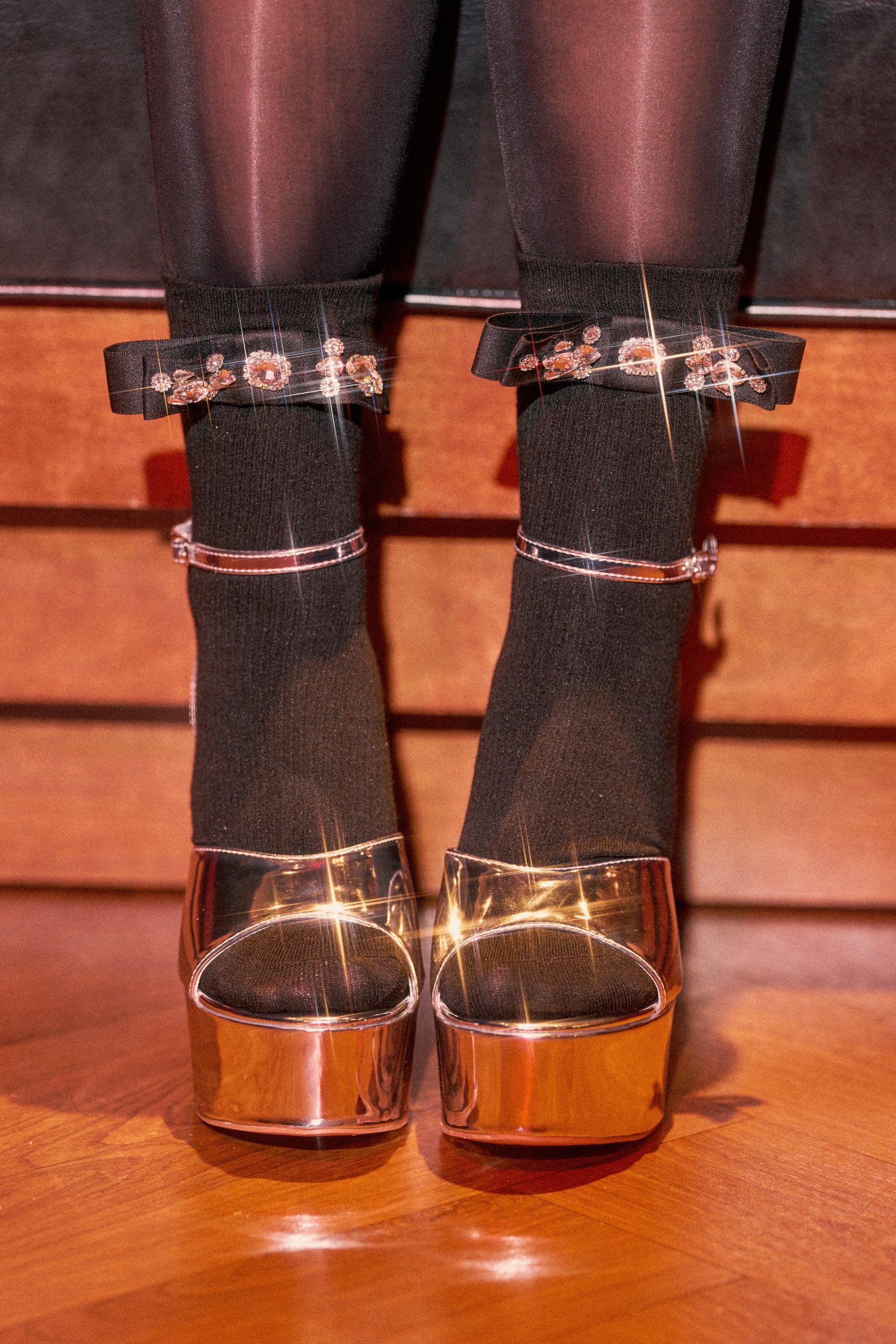 WITH A PUMP EMBELLISHED SOCKS featuring floral embroidery, styled with shiny metallic platform heels and ankle straps, showcased against a wooden floor background. 0