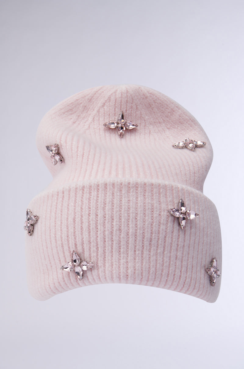 The STAR POWER RHINESTONE BEANIE from the AKIRA Label, in soft pink knit, is decorated with shimmering star-shaped rhinestones set against a light gray background.