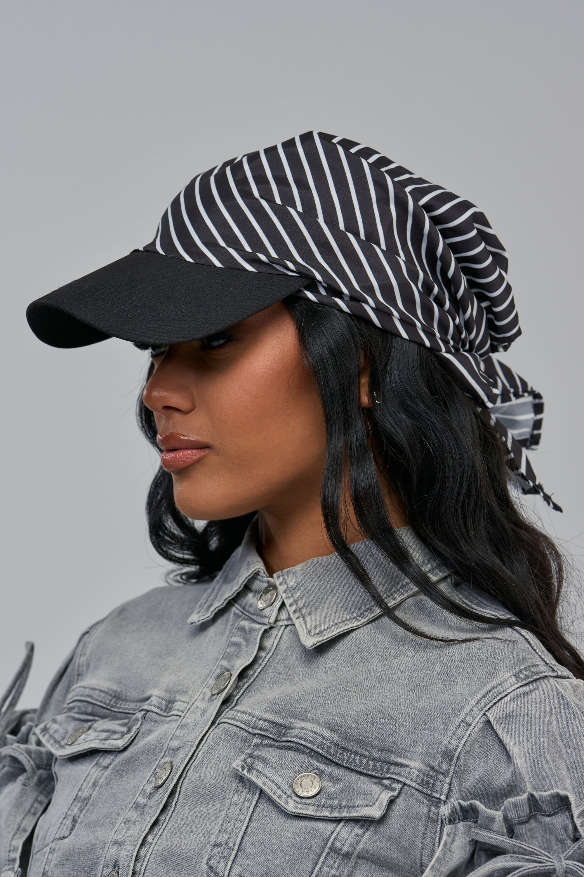 A person wearing a STRIPE SESSION HAT, featuring a black-and-white striped headscarf paired with a solid black baseball cap visor.