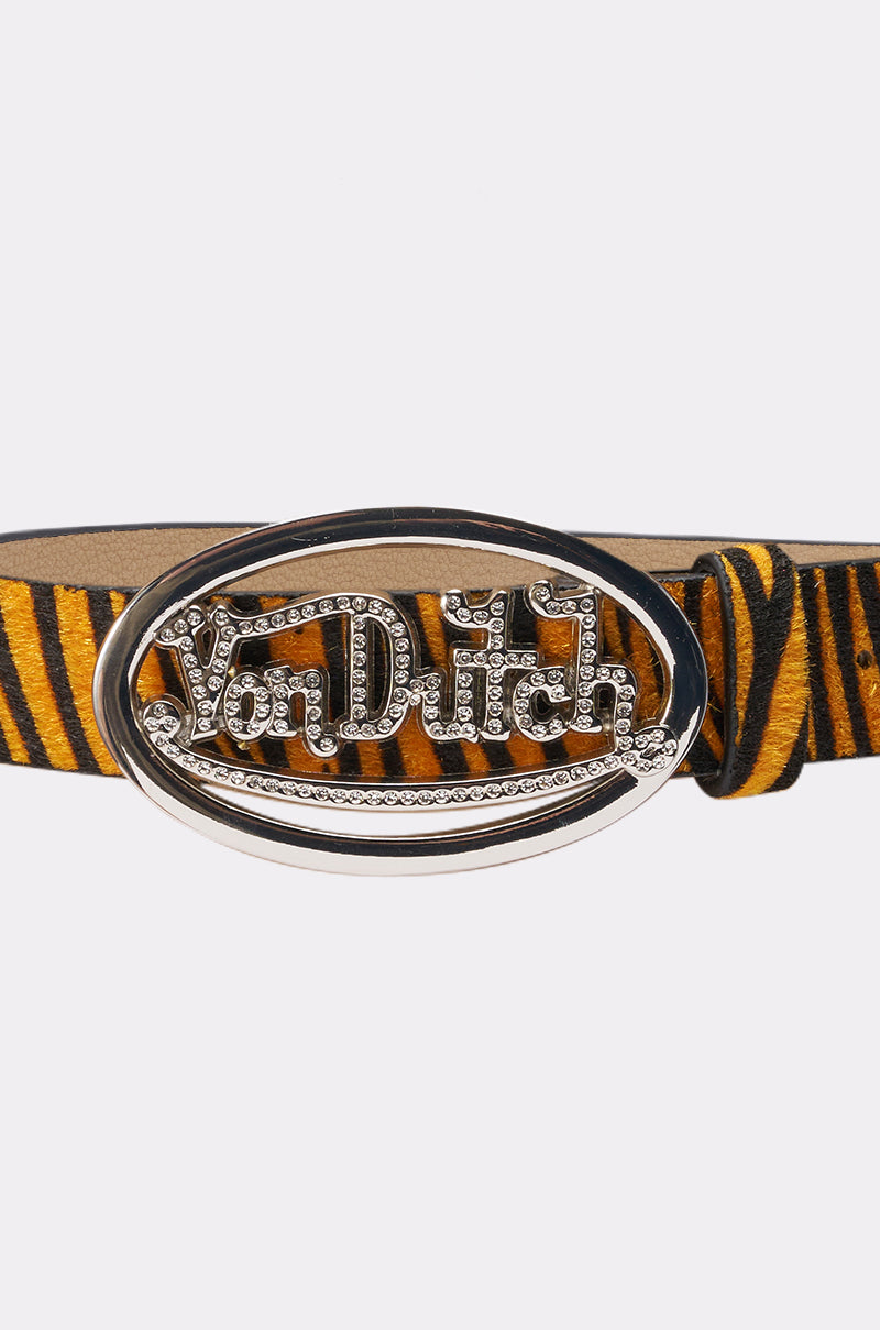 Inspired by Y2K style, the VON DUTCH TIGER BELT features yellow and black faux fur with a bold oval silver buckle encrusted in rhinestones and engraved with the Von Dutch logo. 2