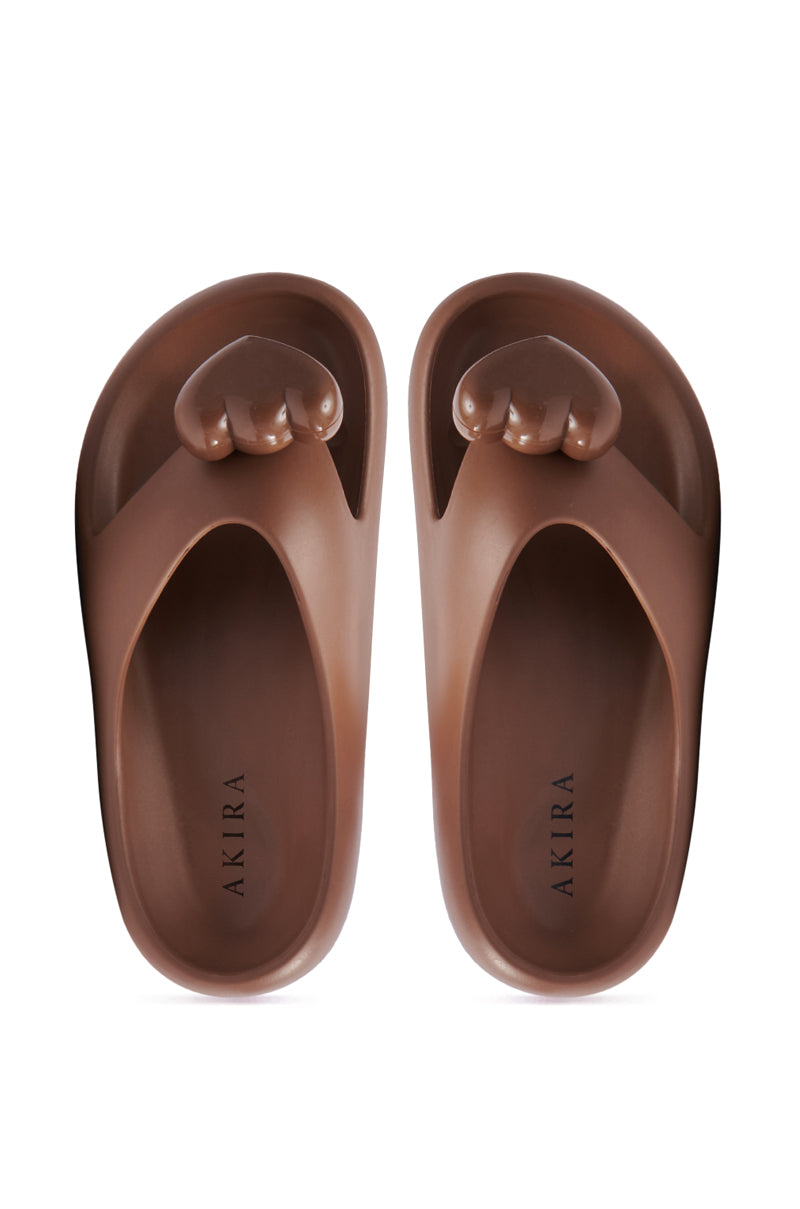 The AKIRA COMPASSION BROWN SANDAL, a casual open-toe slip-on, features bear paw-like design on the uppers and soles imprinted with the "Akira" brand name.