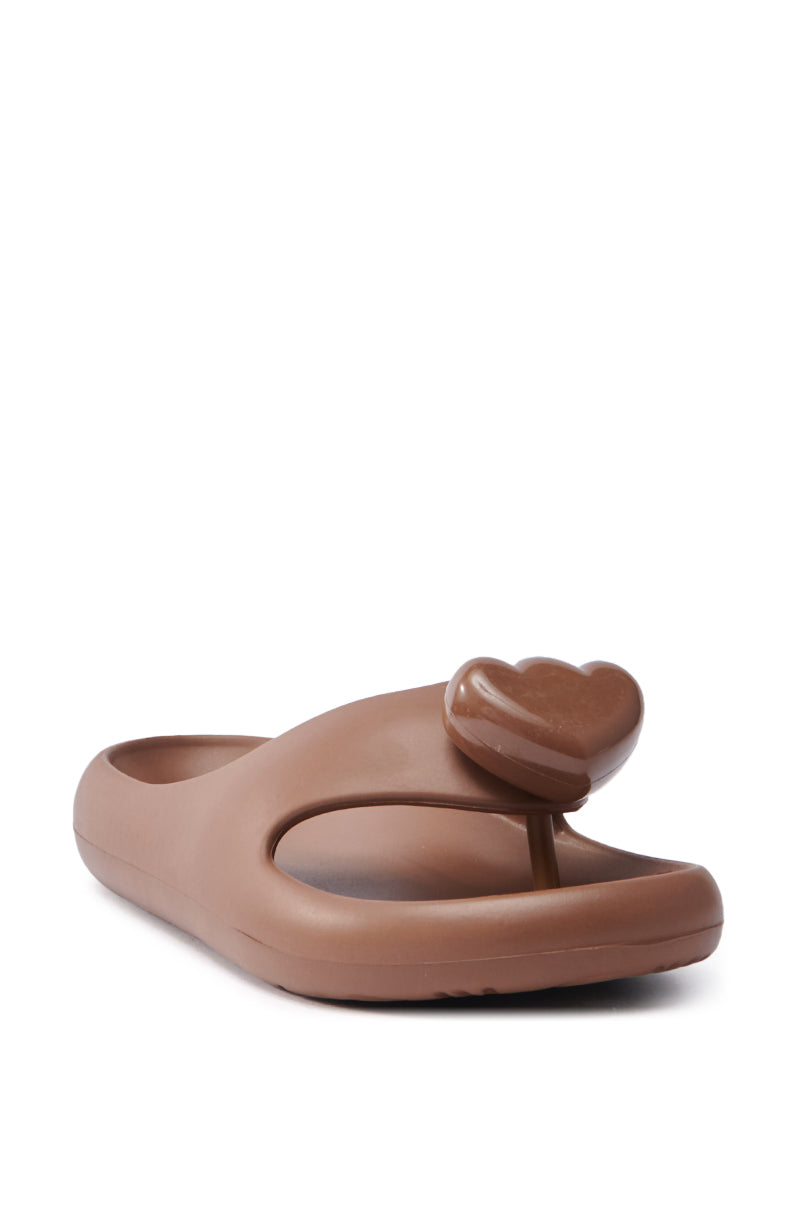 Introducing the AKIRA COMPASSION BROWN SANDAL, a chic slip-on with a heart-shaped accent on the strap. This sandal features an effortless slide-on design and an open-toe style, combining simplicity with modern aesthetics.