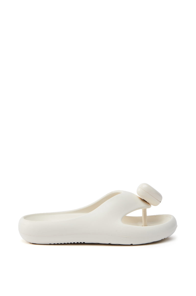 The AKIRA COMPASSION WHITE SANDAL is a minimalist, white rubber slide with a comfortable construction. It features an almond thong toe design, a unique round toe strap, and a chunky sole, all shown against a plain white background.