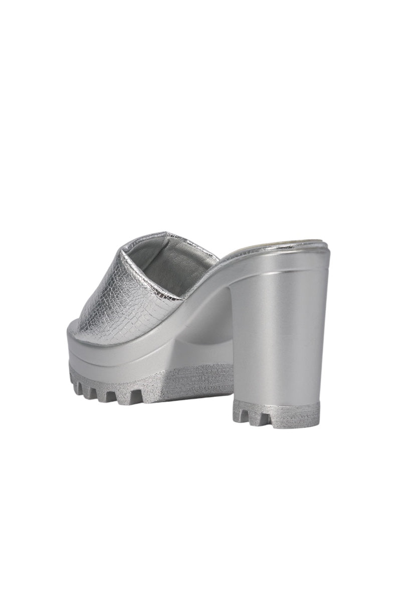 The AKIRA COOLCAT SILVER CROC BLOCK HEEL MULE SANDAL features a textured faux leather upper, open toe, chunky block heel, and ridged lug sole. The back-right photo shows off its bold heel and unique croc texture. 5