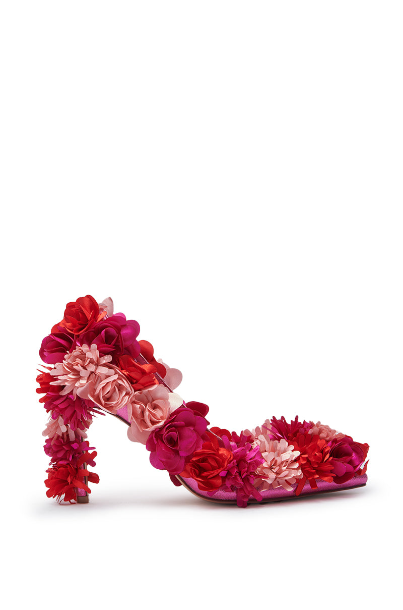 The AZALEA WANG COLLIDGE MULTI FLORAL EMBELLISHED PUMP showcases clusters of red, pink, and magenta fabric flowers on the heel, sides, and toe, set against a plain white background.