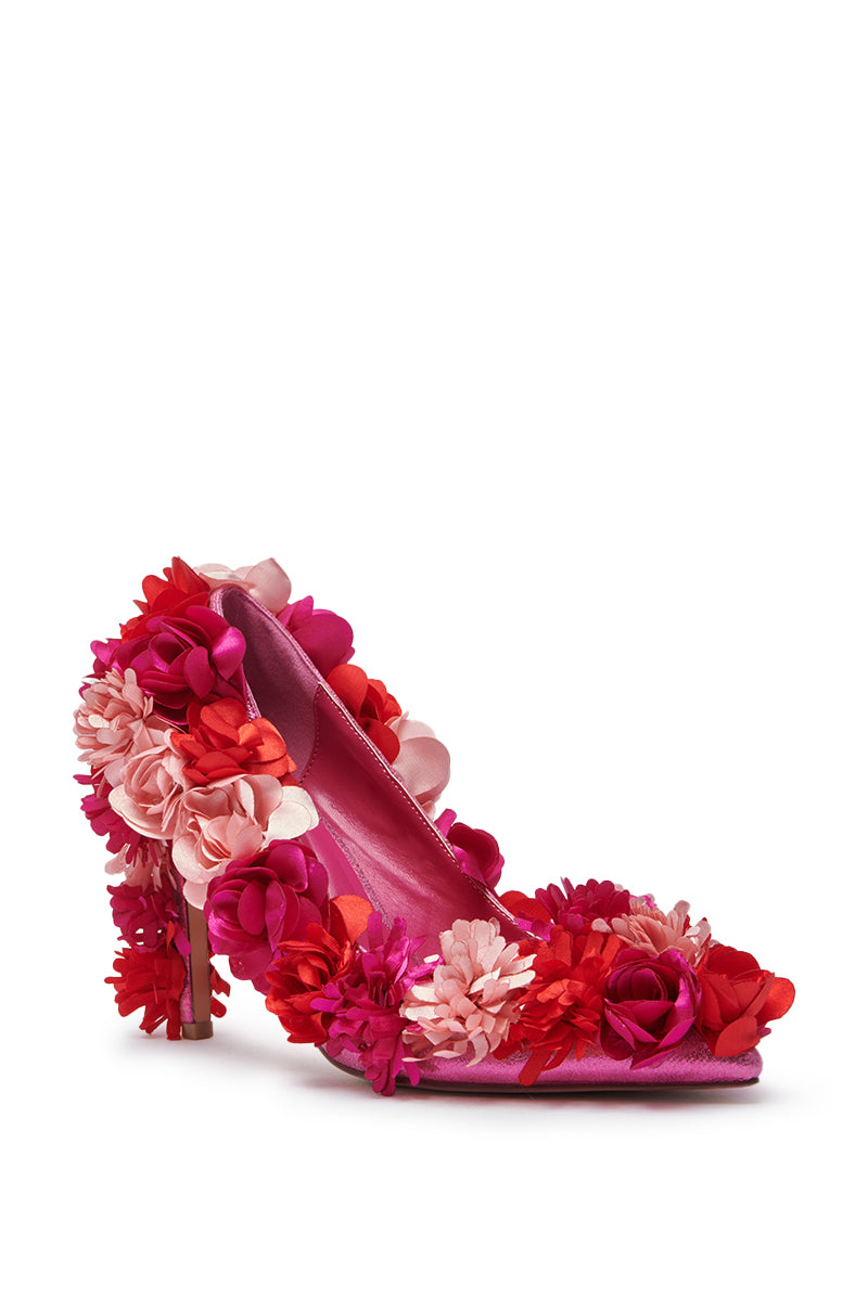The AZALEA WANG COLLIDGE MULTI FLORAL EMBELLISHED PUMP is a high-heeled, pointed-toe shoe adorned with vibrant pink, red, and fuchsia fabric flowers on a white background.
