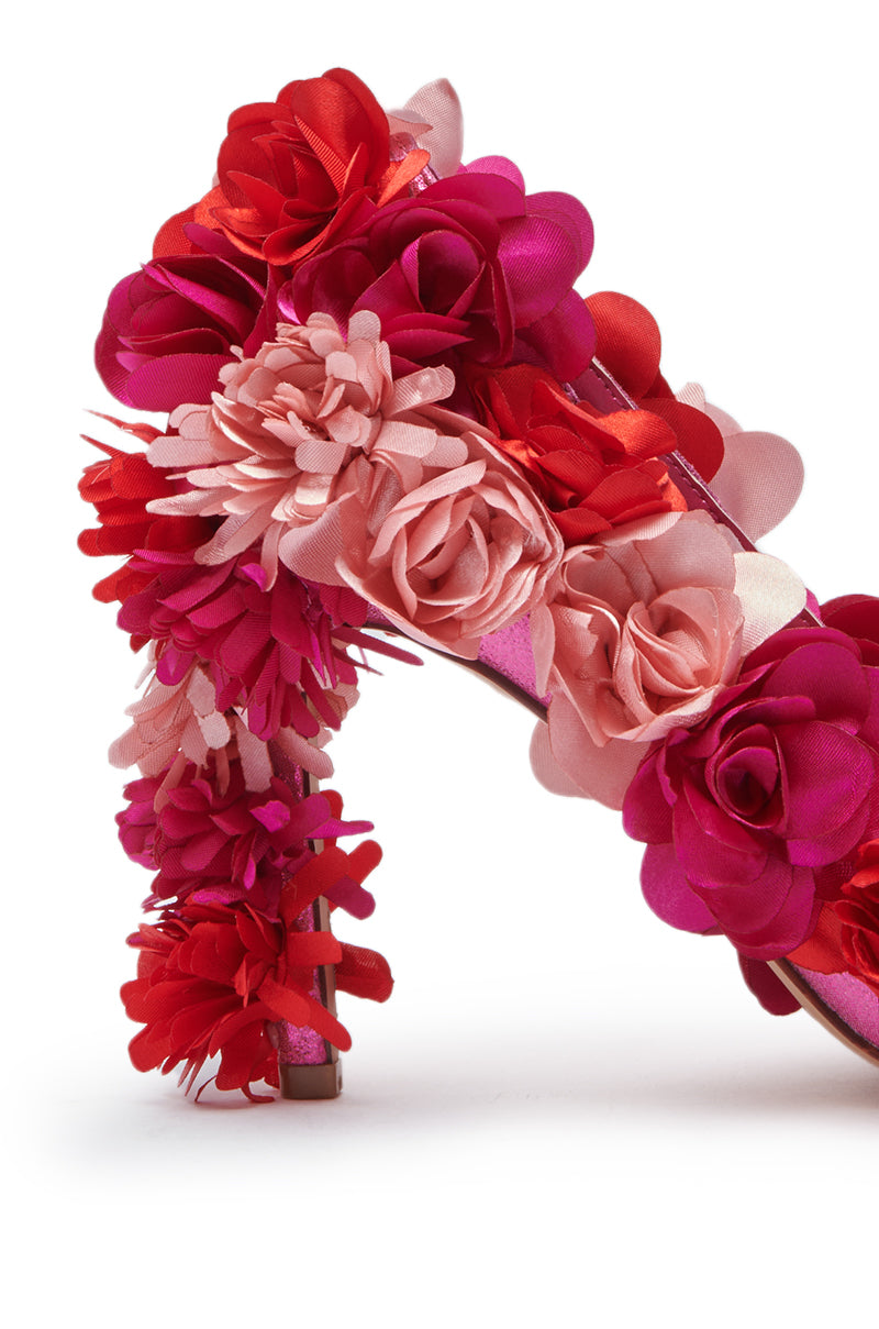 A close-up of the AZALEA WANG COLLIDGE MULTI FLORAL EMBELLISHED PUMP, featuring a stiletto heel and upper adorned with large red, pink, and fuchsia artificial flowers, set against a white background.