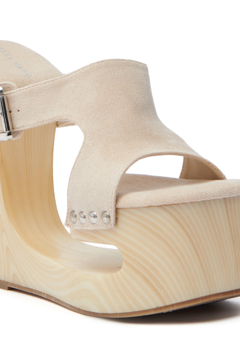 A close-up of the AZALEA WANG COPSE beige sandal highlights its open toe design, metal side studs, and a chunky wedge heel with a wood-textured platform sole.