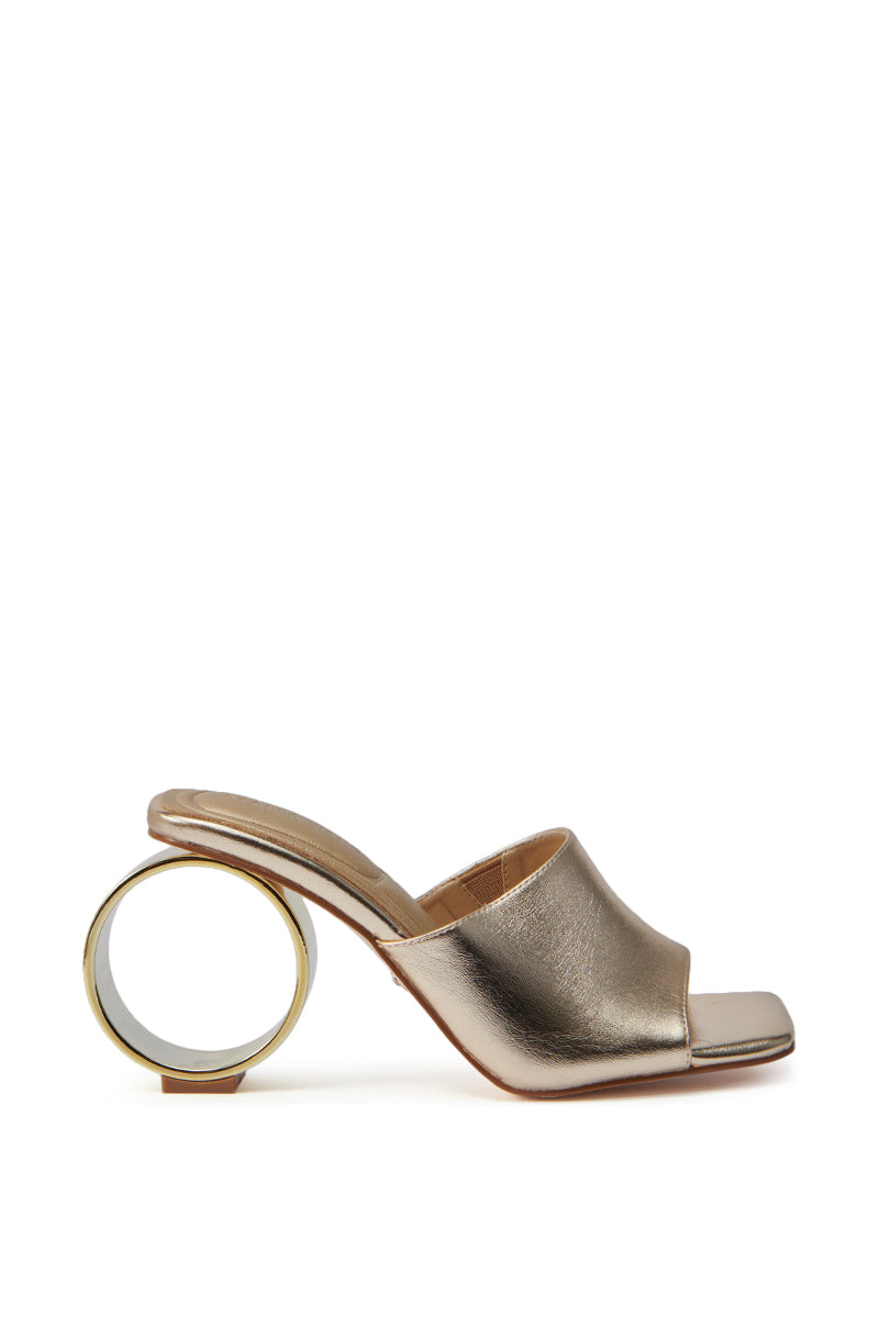 The AZALEA WANG CORABELLE GOLD NOVELTY HEEL SANDAL is a gold metallic mule with an open toe and sculptural ring heel, displayed on a white background. 4
