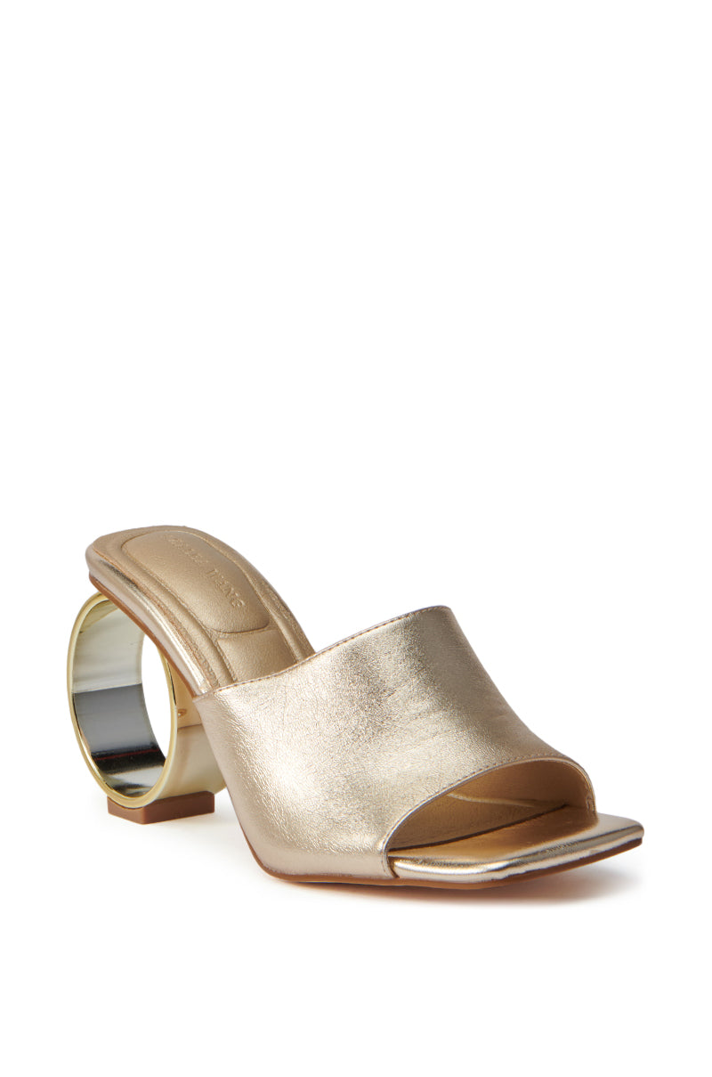 The AZALEA WANG CORABELLE GOLD NOVELTY HEEL SANDAL features a metallic gold finish, open square toe, wide strap, and a bold circular heel, showcased elegantly against a white background. 5