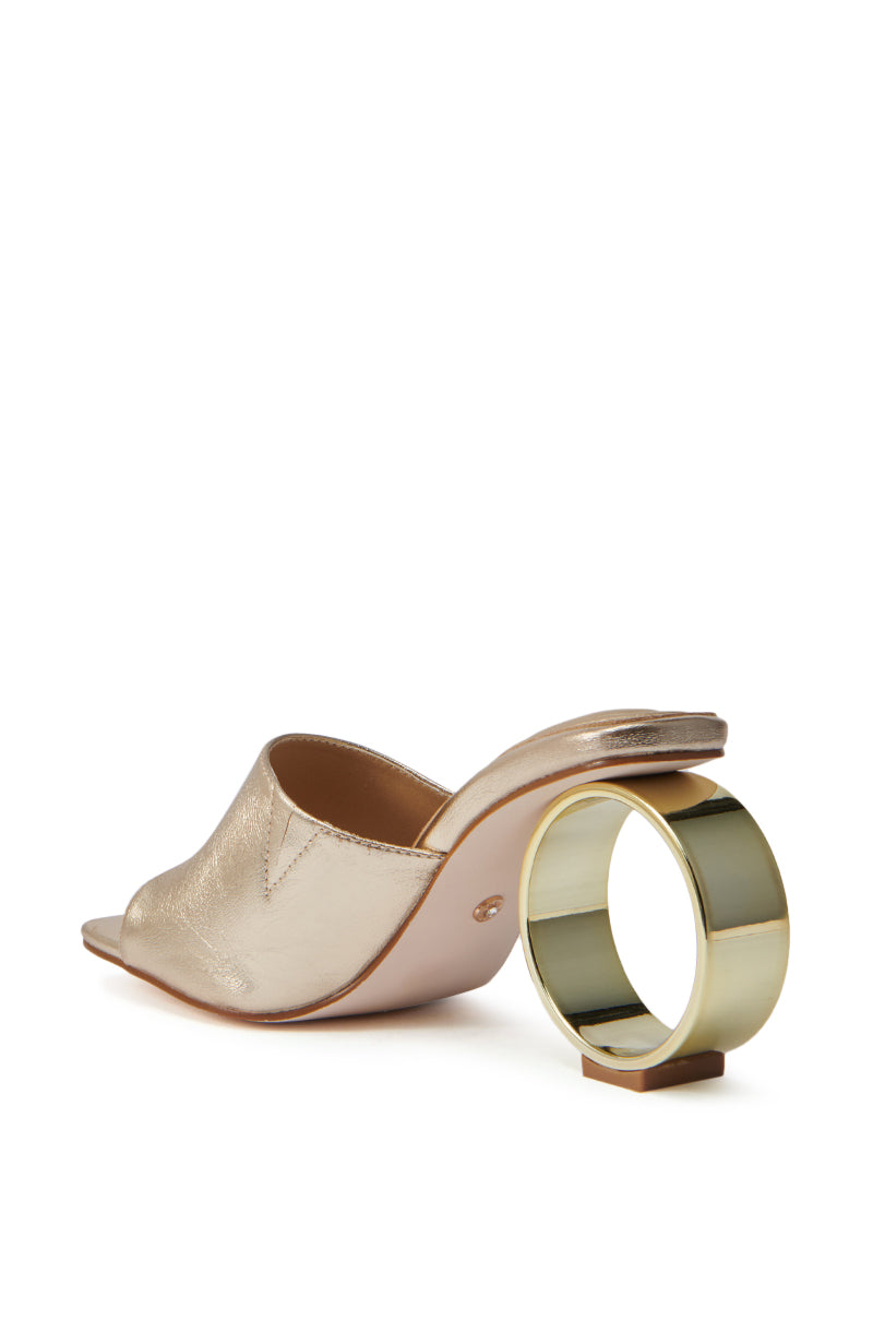 The AZALEA WANG CORABELLE GOLD NOVELTY HEEL SANDAL features an open square toe and a thick, circular novelty heel, showcased from the rear on a white background. 6