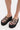 Someone stands on a light surface wearing AZALEA WANG CORLISS LEOPARD FLATFORM SANDALS, which feature thick black soles, sparkly sequined leopard print straps, and a cushioned faux leather insole.