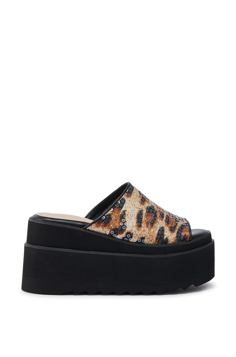 The AZALEA WANG CORLISS LEOPARD FLATFORM SANDAL features a sequined leopard print upper, an open toe, a thick black sole, and a cushioned faux leather insole for comfort.