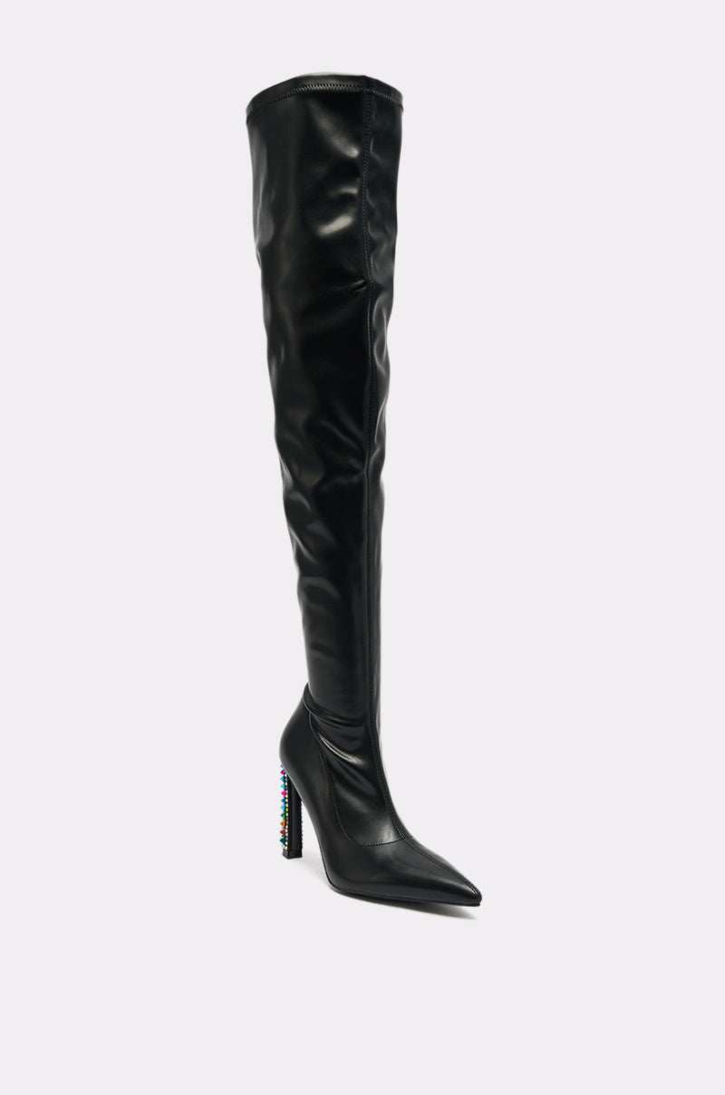 The AZALEA WANG COSMIC BLING BLACK BOOT features black faux leather, a pointed toe, and an over-the-knee design with a high block heel adorned with colorful embellishments. Displayed against a plain light background.