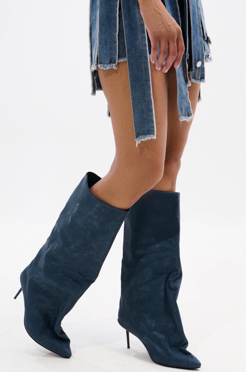 Wearing a denim mini skirt with fringed strips and slouchy AZALEA WANG COUTURE CRAZY BLUE LUXE SHINE LOOK BOOTs, a person stands against a plain white background.