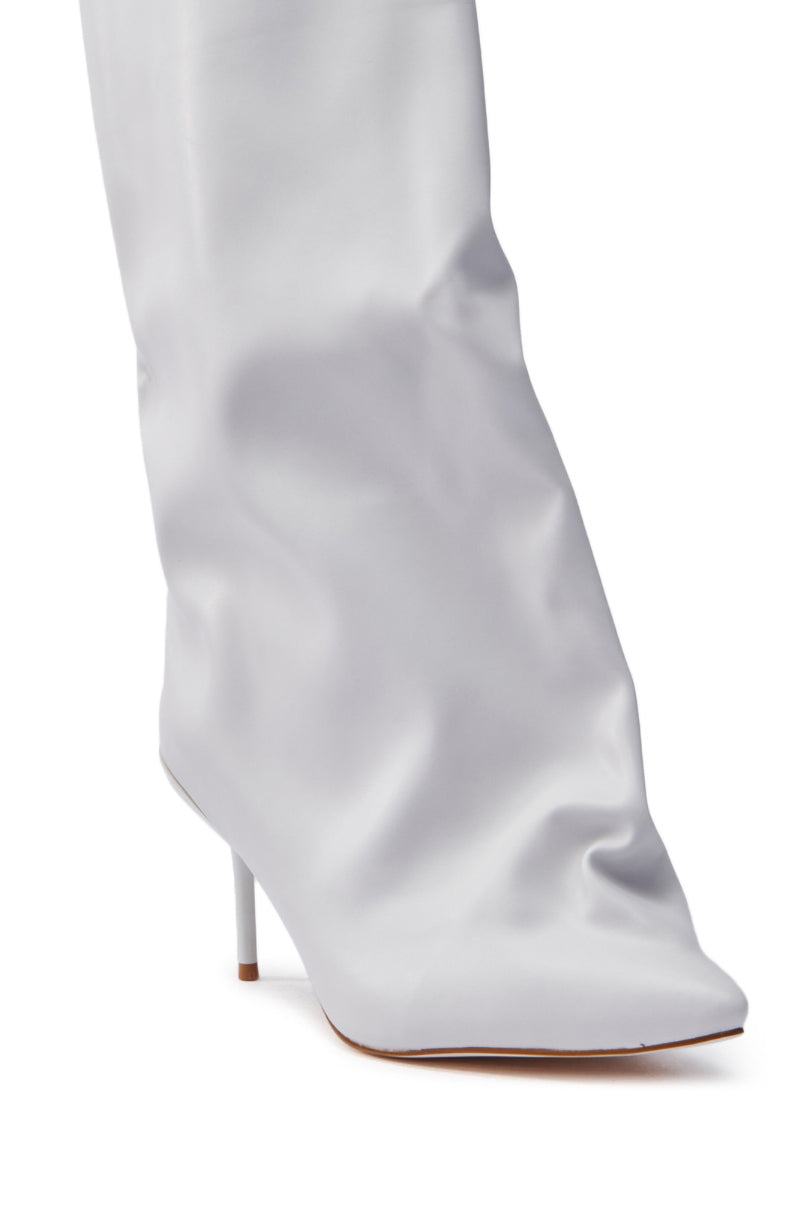 Close-up of the AZALEA WANG COUTURE CRAZY BONE BOOT, a white knee-high boot with a pointed toe, slender stiletto heel, and smooth faux leather subtly slouched near the ankle.