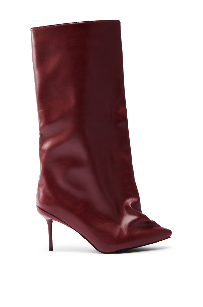 The AZALEA WANG COUTURECRAZY BURGUNDY BOOT is a knee-high, slouchy, maroon faux leather boot with a pointed toe and slender stiletto heel, showcased against a plain white backdrop.