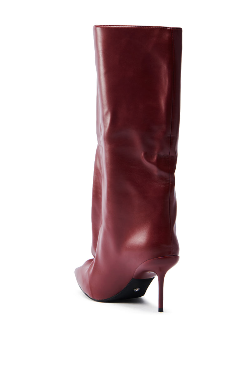 The AZALEA WANG COUTURECRAZY BURGUNDY BOOT is a tall, faux leather piece featuring a pointed toe and slender stiletto heel. Viewed from the back and side, it highlights its sleek, smooth burgundy texture.
