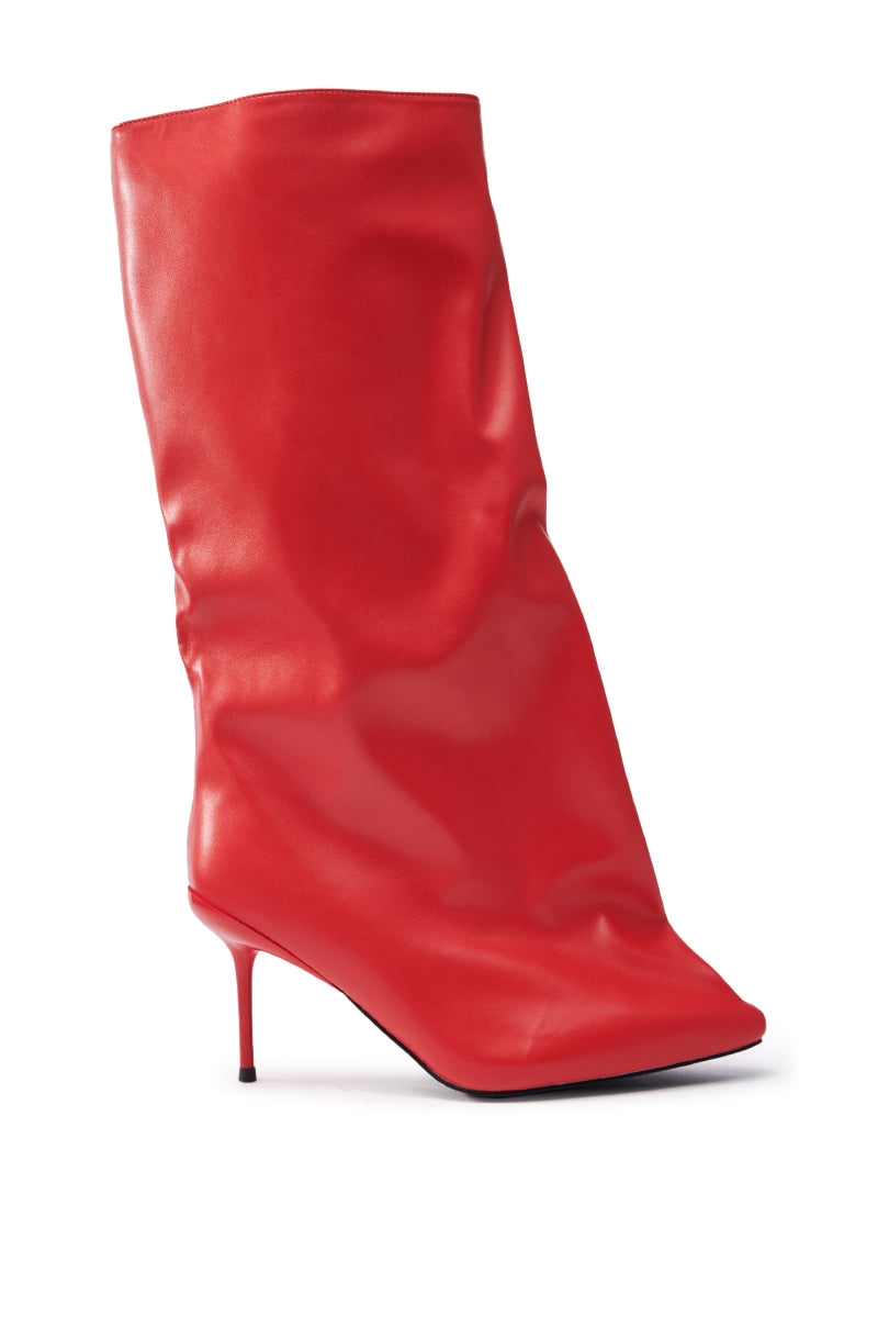 The AZALEA WANG COUTURE CRAZY RED BOOT is a knee-high, bright red slouchy boot made from vegan leather, featuring a pointed toe and thin stiletto heel, set on a plain white background.