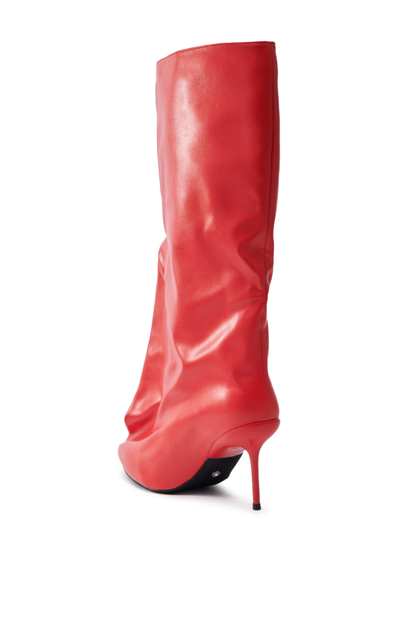 The AZALEA WANG COUTURE CRAZY RED BOOT is displayed against a white background, showcasing a shiny vegan leather finish and slouchy design with a pointed toe and slender stiletto heel.