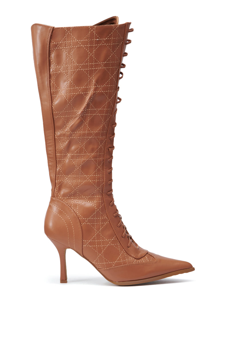 Introducing the CREATOR TAN LACE UP STILETTO BOOT: a brown, knee-high boot crafted from leather, featuring a pointed toe and a stiletto heel. This elegant design is enhanced with decorative stitching in a quilted diamond pattern.
