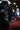 A person wearing black faux leather pants with frayed hems and AZALEA WANG CRESSINDA BLACK GUNMETAL DOME STUD STILETTO BOOTIES rests their legs on a red upholstered chair in a dimly lit room.