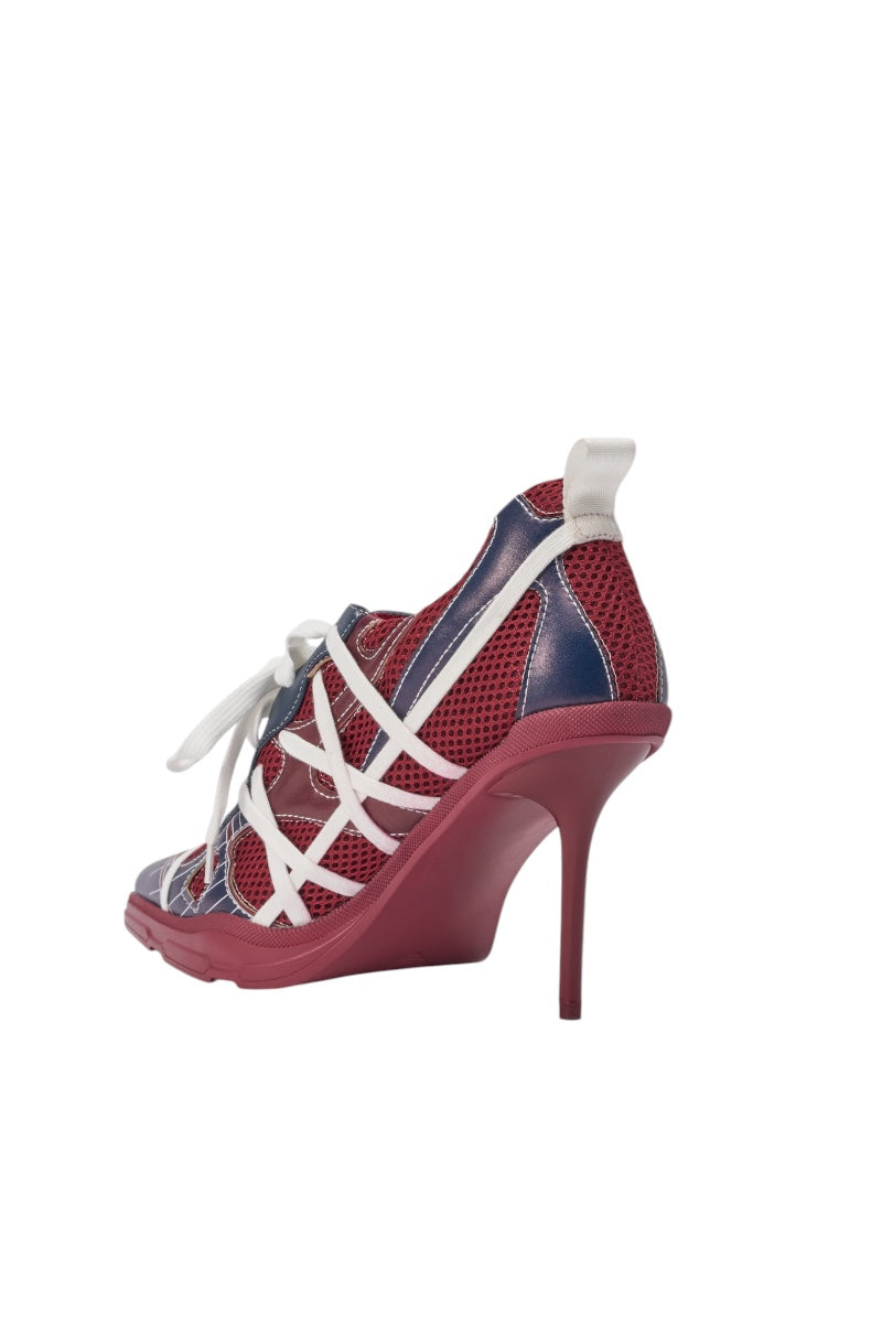 The AZALEA WANG CROSS WALK BURGUNDY STILETTO SNEAKER HEEL features a red sole, red mesh upper, navy blue accents, and white crisscross straps and laces, shown in a side view on a white background. 5