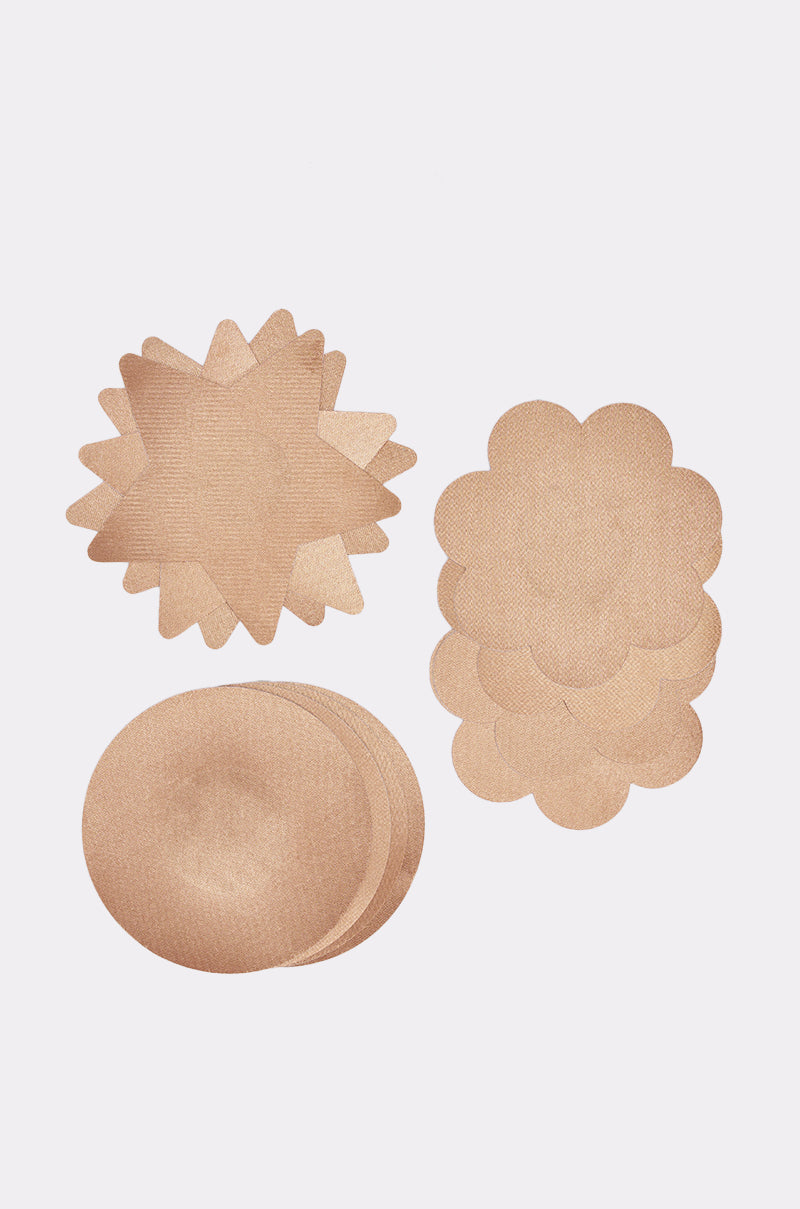 The TITSY TAN NIPPY 6 PACK includes skin-toned adhesive nipple covers in starburst, flower, and circle shapes, shown on a white background for a seamless finish under clothing. 1