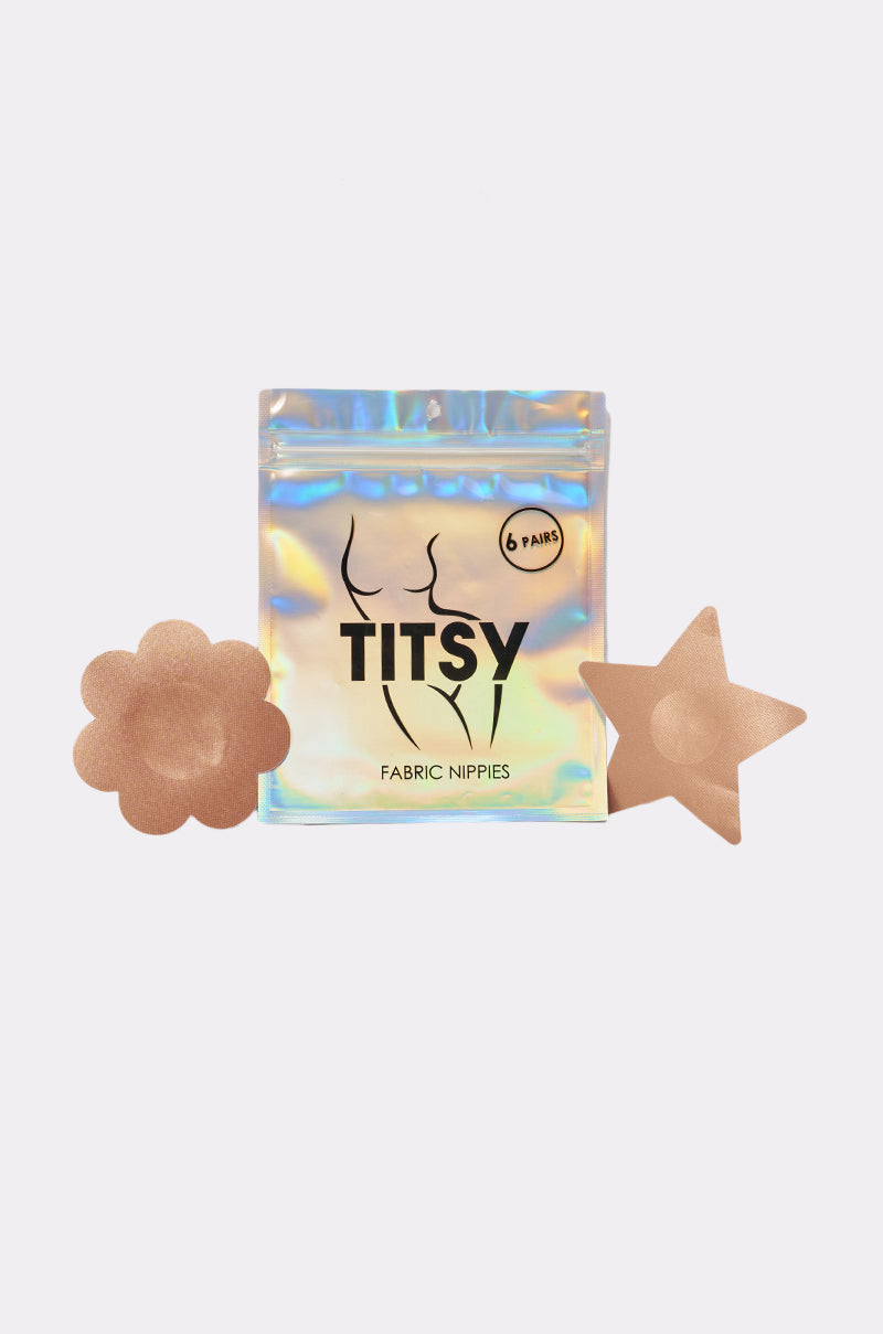Holographic TITSY TAN NIPPY 6 PACK labeled "Fabric Nippies" with two seamless nipple covers in flower and star shapes beside the package; text shows it contains 6 pairs. 2