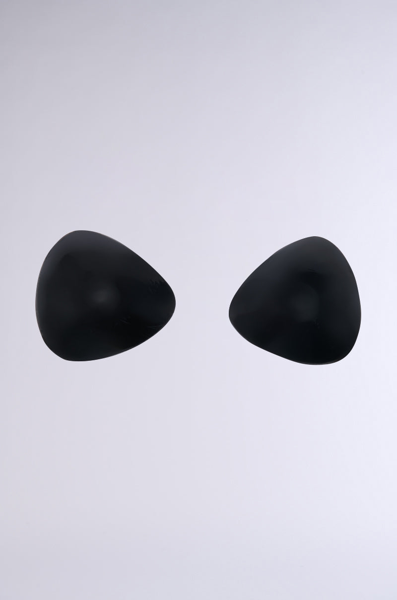 Two asymmetrical triangular objects, resembling ULTIMATE PUSHUP NIPPIE CUTLETS IN BLACK, are placed on a simple light gray background. 0