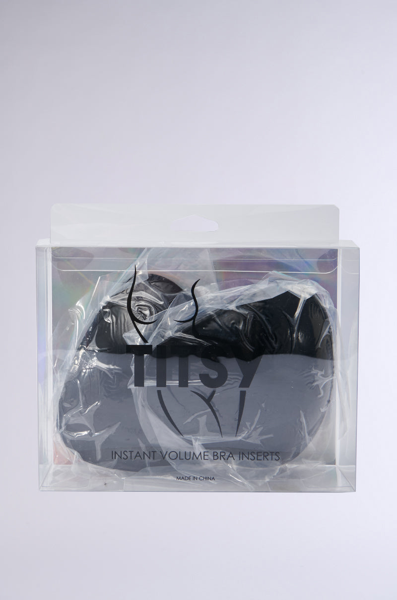 A pair of black bra inserts is visible through clear plastic packaging labeled "ULTIMATE PUSHUP NIPPIE CUTLETS IN BLACK," designed to enhance cleavage volume.