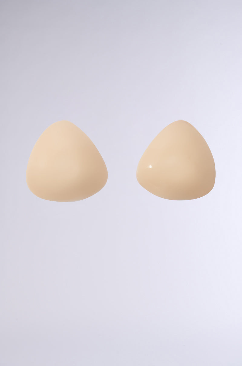 The ULTIMATE PUSHUP NIPPIE CUTLETS IN NUDE are triangular silicone breast forms with an adhesive backing, designed for optimal cleavage enhancement. They are smooth and slightly shiny, shown on a light gray background. 0