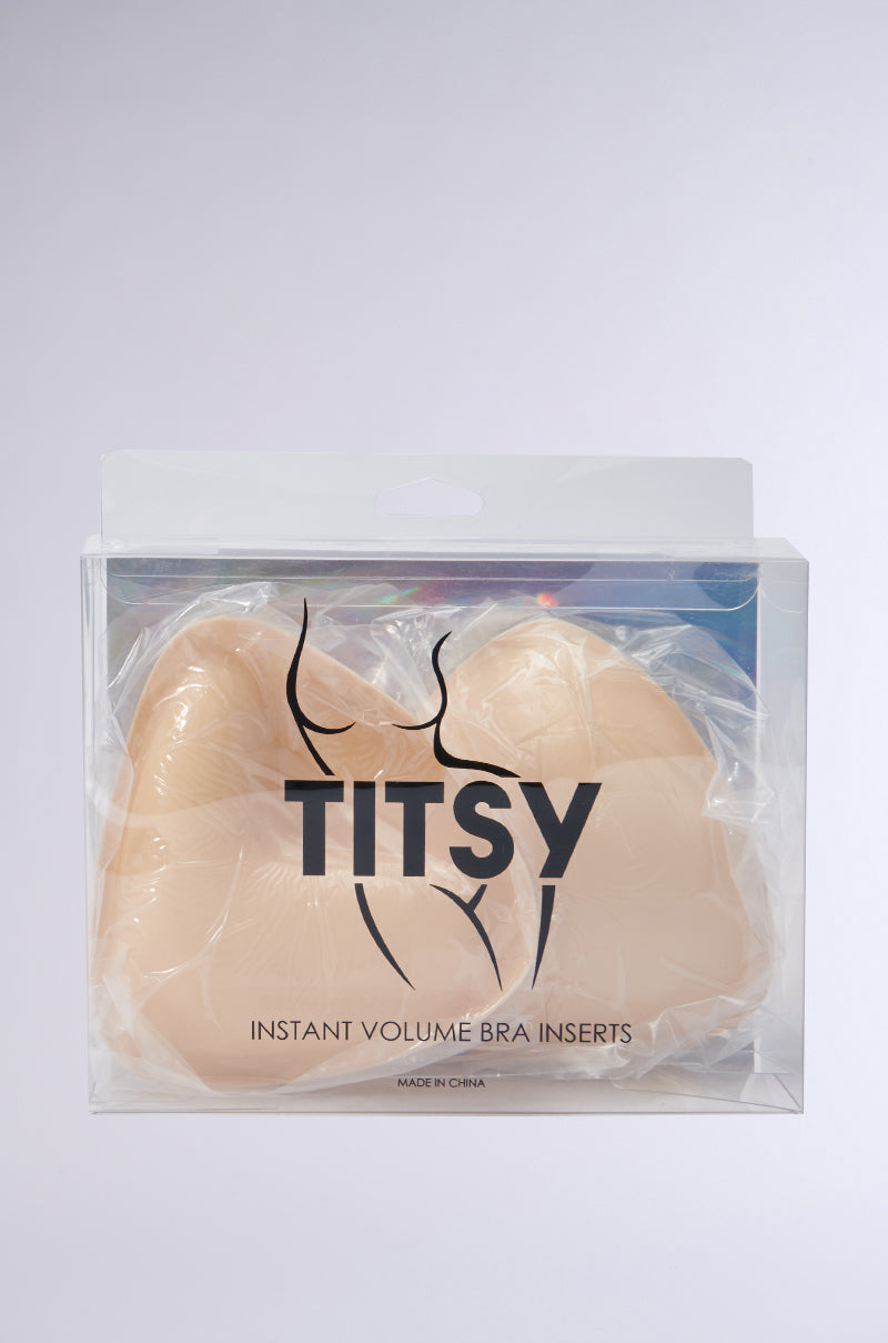 The "ULTIMATE PUSHUP NIPPIE CUTLETS IN NUDE" come in transparent packaging, revealing minimalist beige inserts designed to enhance cleavage and subtle elegance against a neutral background.