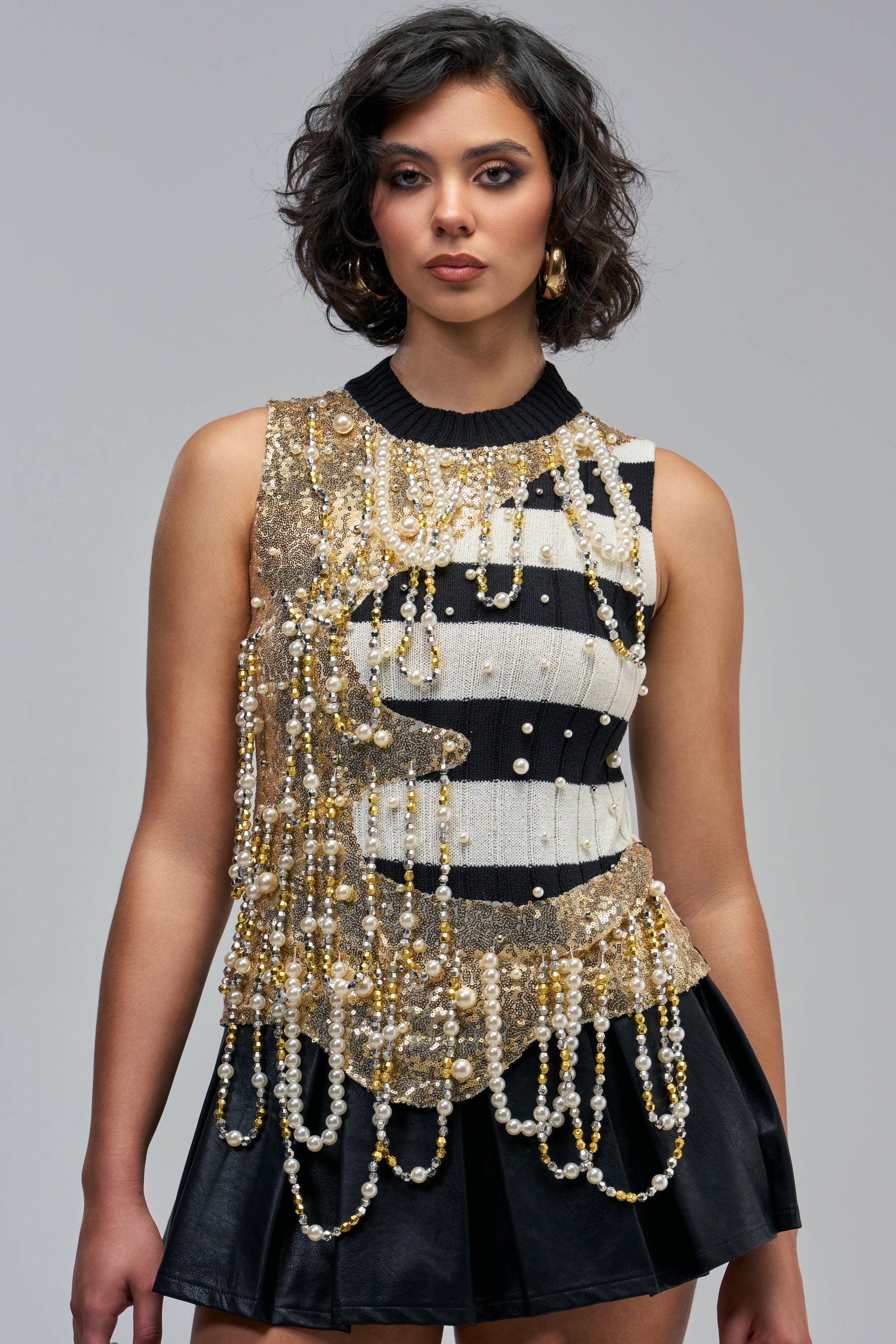 A WHOLE PEARL MOMENT STRIPED TOP is a sleeveless, black-and-white striped knit top embellished with gold sequins and cascading strands of faux pearls.