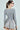 A woman with a ponytail, glasses, and hoop earrings is seen from behind. She wears the 