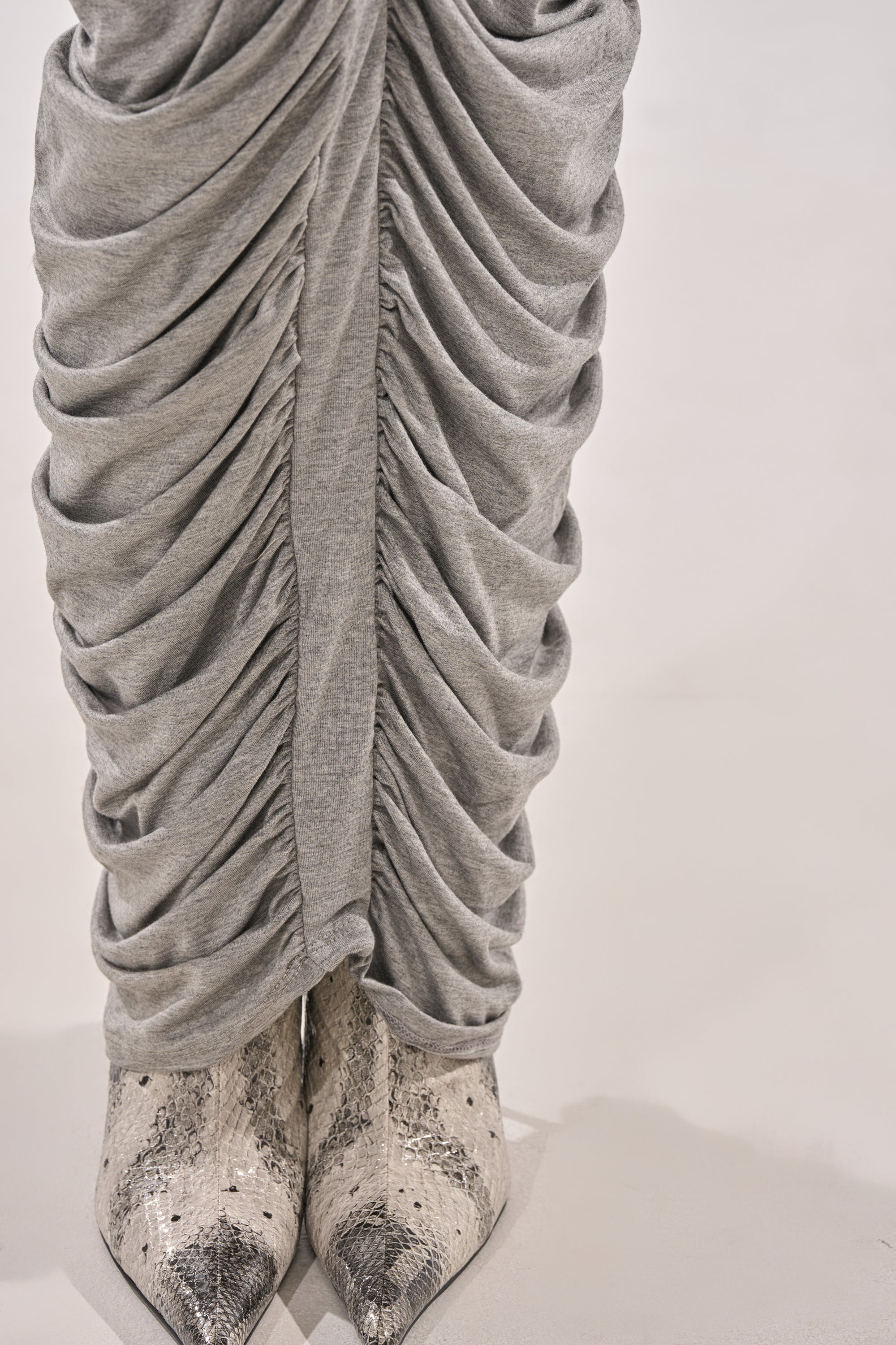 Close-up of the CLASSIC CHIC STRAPLESS MAXI DRESS, featuring elegant ruched panel detailing, styled with pointed-toe snakeskin boots on a light-colored surface. 6