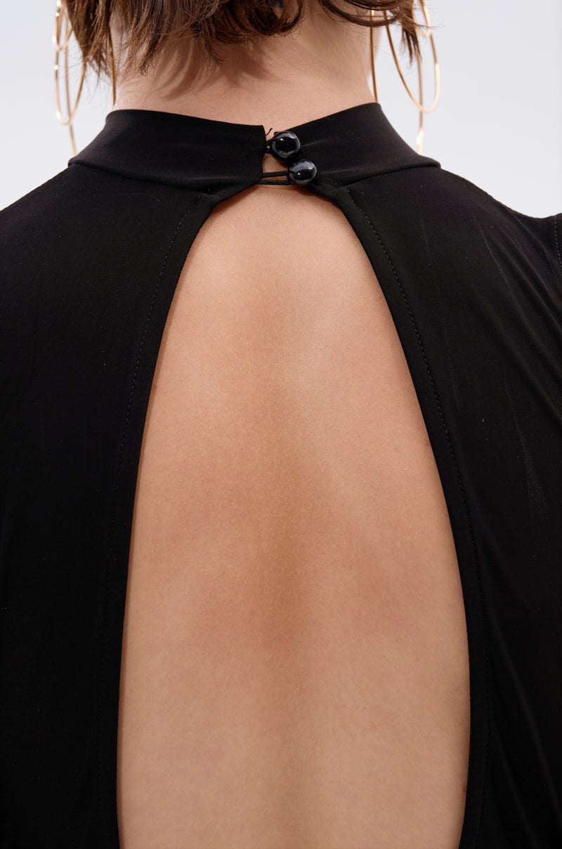 Close-up of a person’s upper back wearing the CAN'T REACH ME PLUNGING MINI DRESS WITH HARDWARE, featuring an oval open back and two black collar buttons. Large hoop earrings are partially visible.