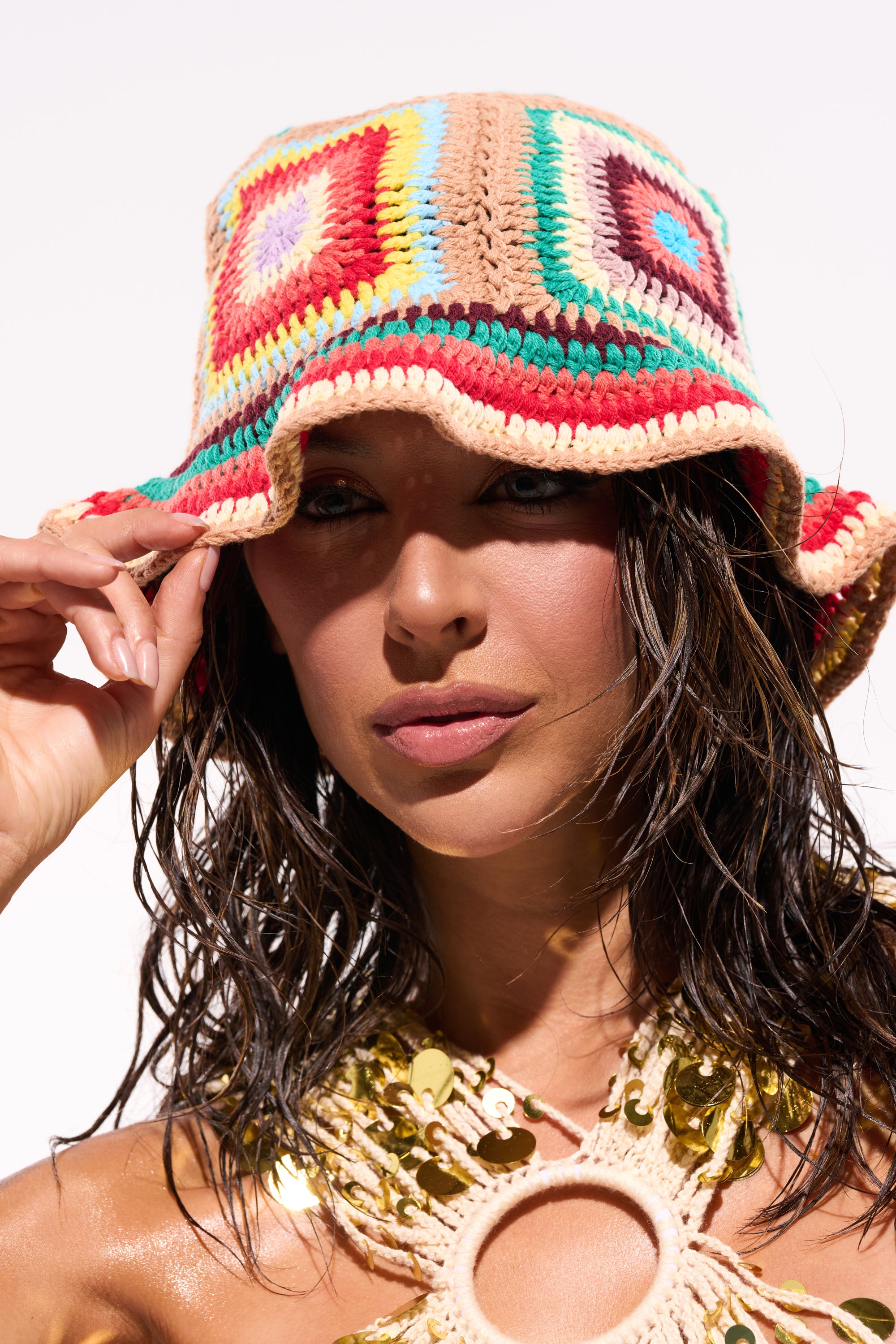 A woman with wet hair wears the NEUTRAL VIBES CROCHET BUCKET HAT and a gold sequined crochet top, posing in bright sunlight against a white background. 0