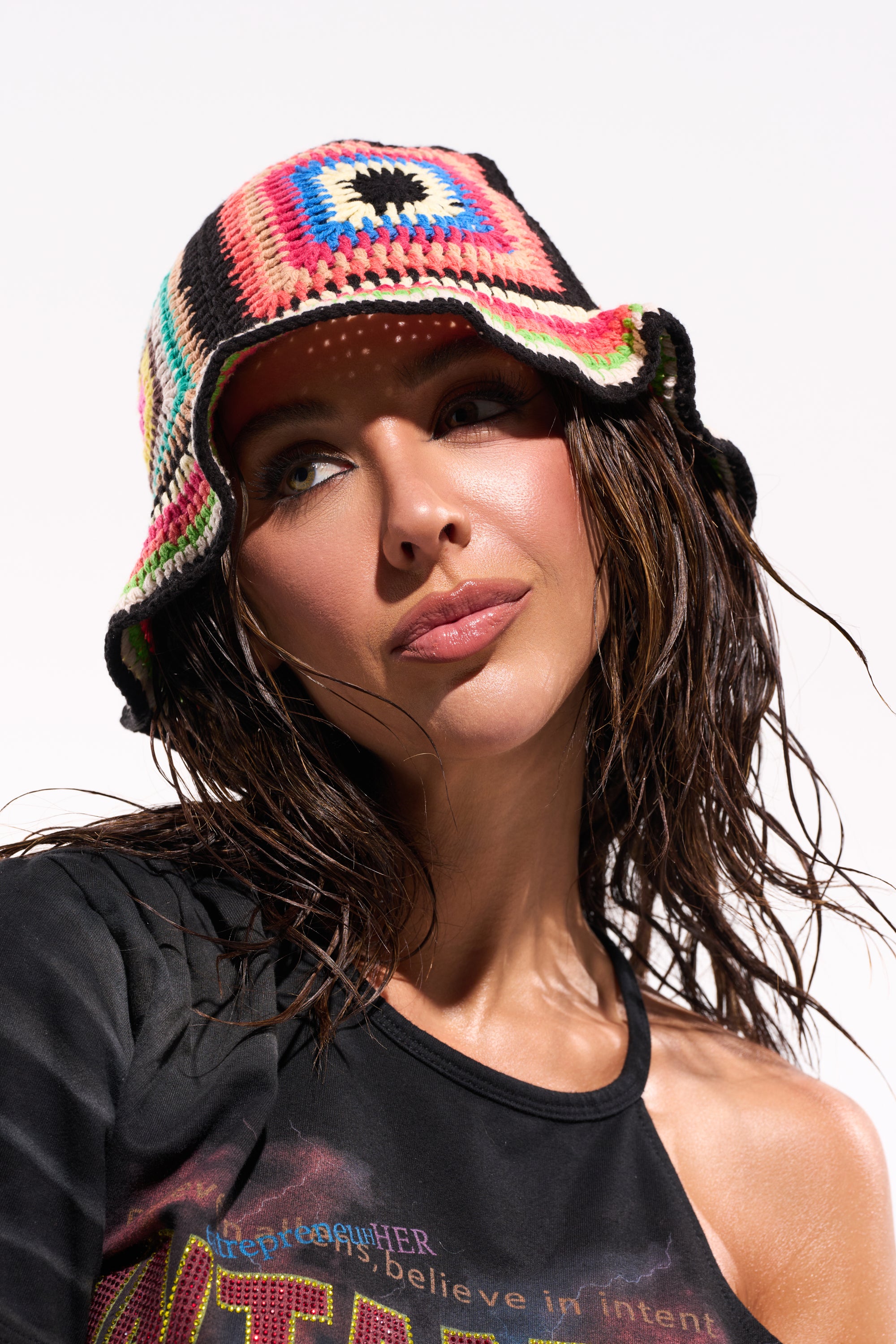 A woman with wet hair wears the DND CROCHET BUCKET HAT and a black off-shoulder top, gazing slightly upward against a plain white background for a retro-cool vibe. 0