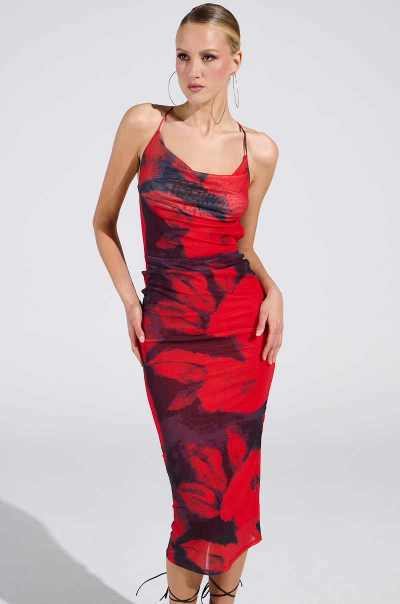 A woman models the ROSEY MIDI DRESS in red, featuring a body-hugging fit, bold black abstract floral print, and open-back design. She wears hoop earrings with side-parted hair styled back against a plain white background.
