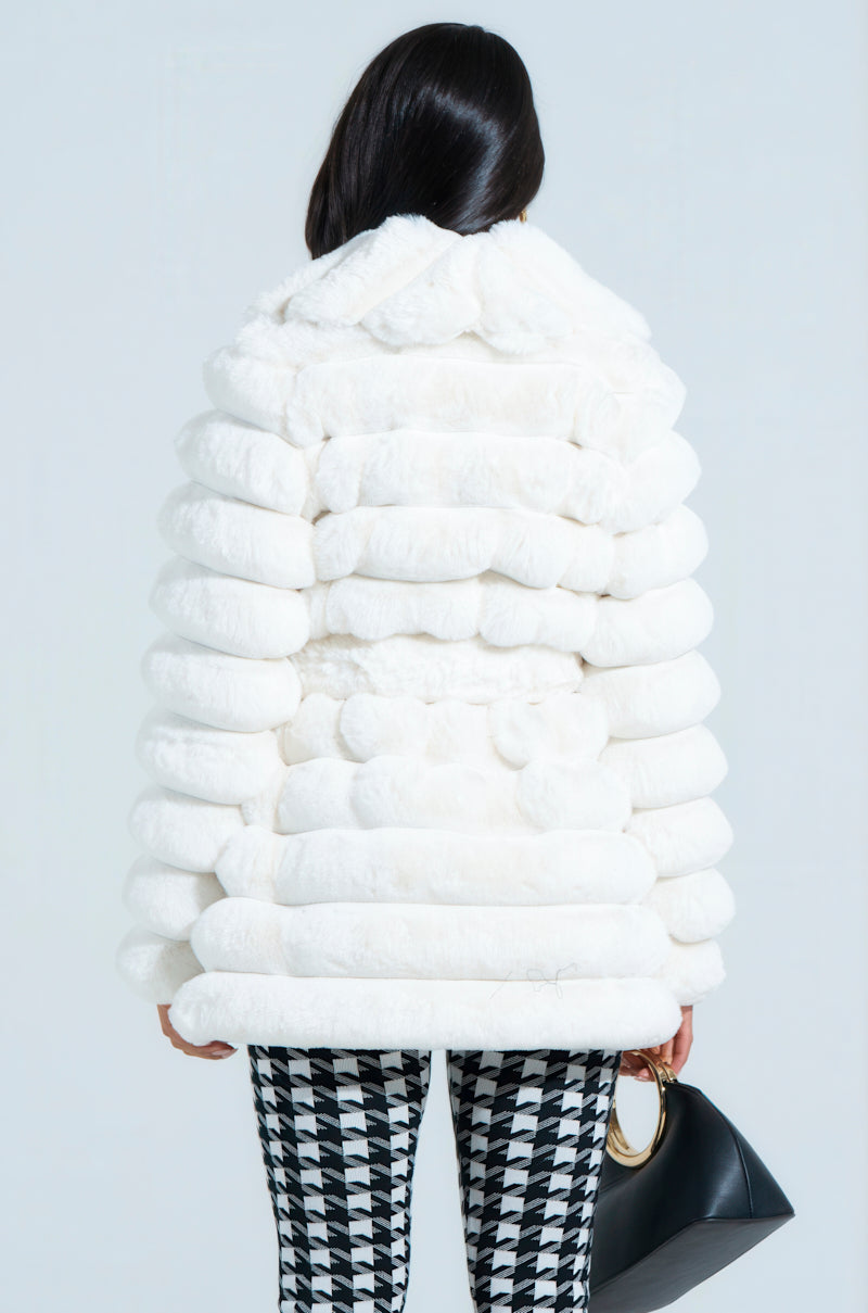 Rear view of a person wearing an oversized silhouette, with the LANA POPCORN FAUX FUR JACKET and black-and-white houndstooth pants, holding a black handbag in their right hand against a light gray background.