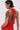 A person with short, slicked-back hair and hoop earrings models the ALWAYS BEST DRESSED MINI DRESS IN RED—a curve-hugging, textured mini dress with an open back—revealing tattoos on their upper arms and back against a plain background.