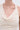 Close-up of a person wearing the ALWAYS BEST DRESSED MIDI DRESS IN IVORY, featuring a cream-colored, textured fabric with a cowl neckline, draped detail, and geometric pleated pattern. The background is plain and light-colored.