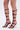 Wearing the AZALEA WANG DAGON LIQUID LUXE CAGED SANDAL—faux patent leather gladiator heels with maroon straps, multiple silver buckles, knee-high design, open square toe, and metallic flared stiletto heel.